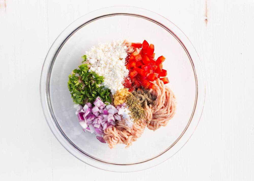 Ingredients for greek chicken burgers in a glass bowl.