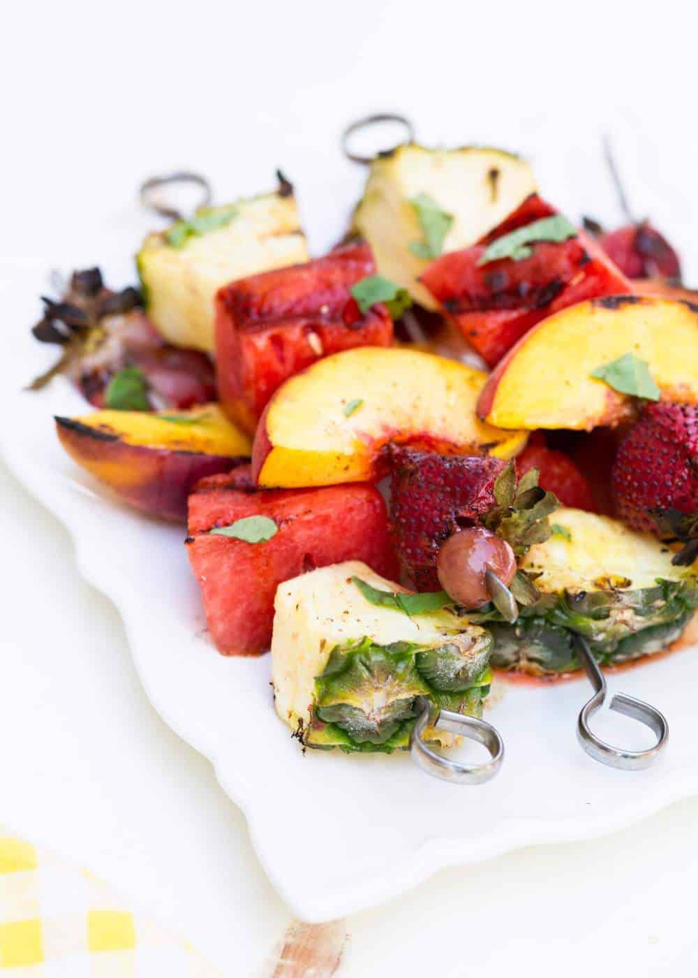 Grilled fruit kabobs on a white plate.