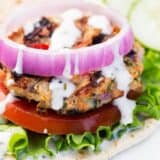 greek chicken burger with lettuce, tomato and onion