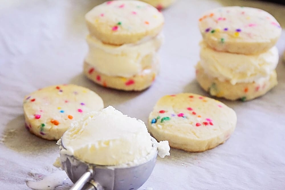 Assembling sugar cookie sandwiches with vanilla ice cream.