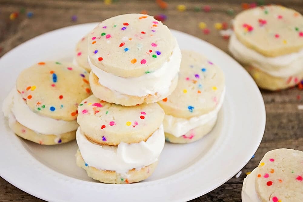 Sugar cookie ice cream sandwiches stacked on a plate.