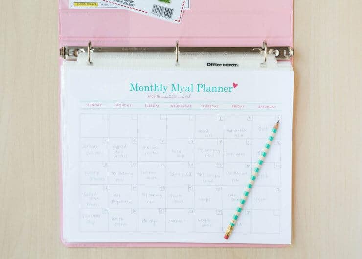 a monthly meal planner in a binder with a pencil 