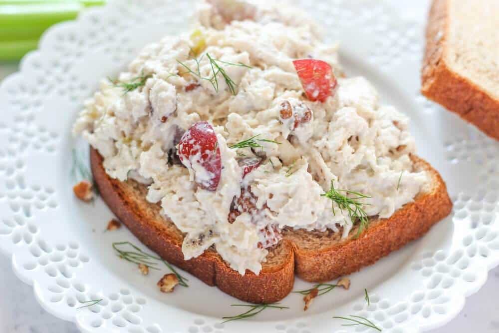 Shredded chicken salad on a piece of bread on a white plate.