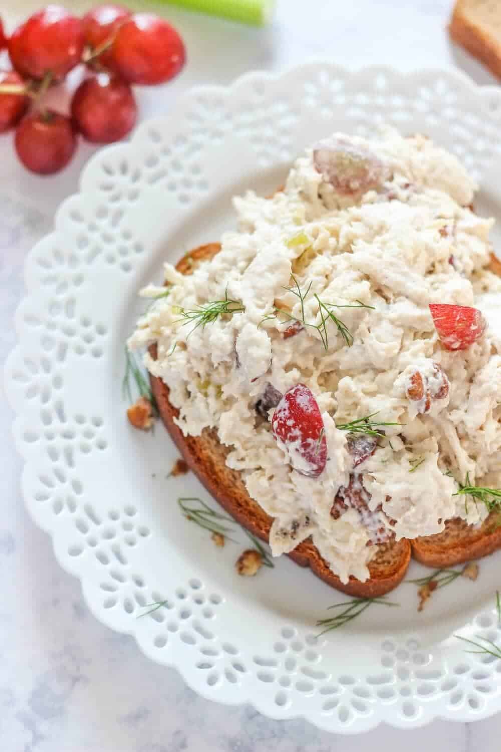 Shredded chicken salad on a piece of bread topped with fresh dill.