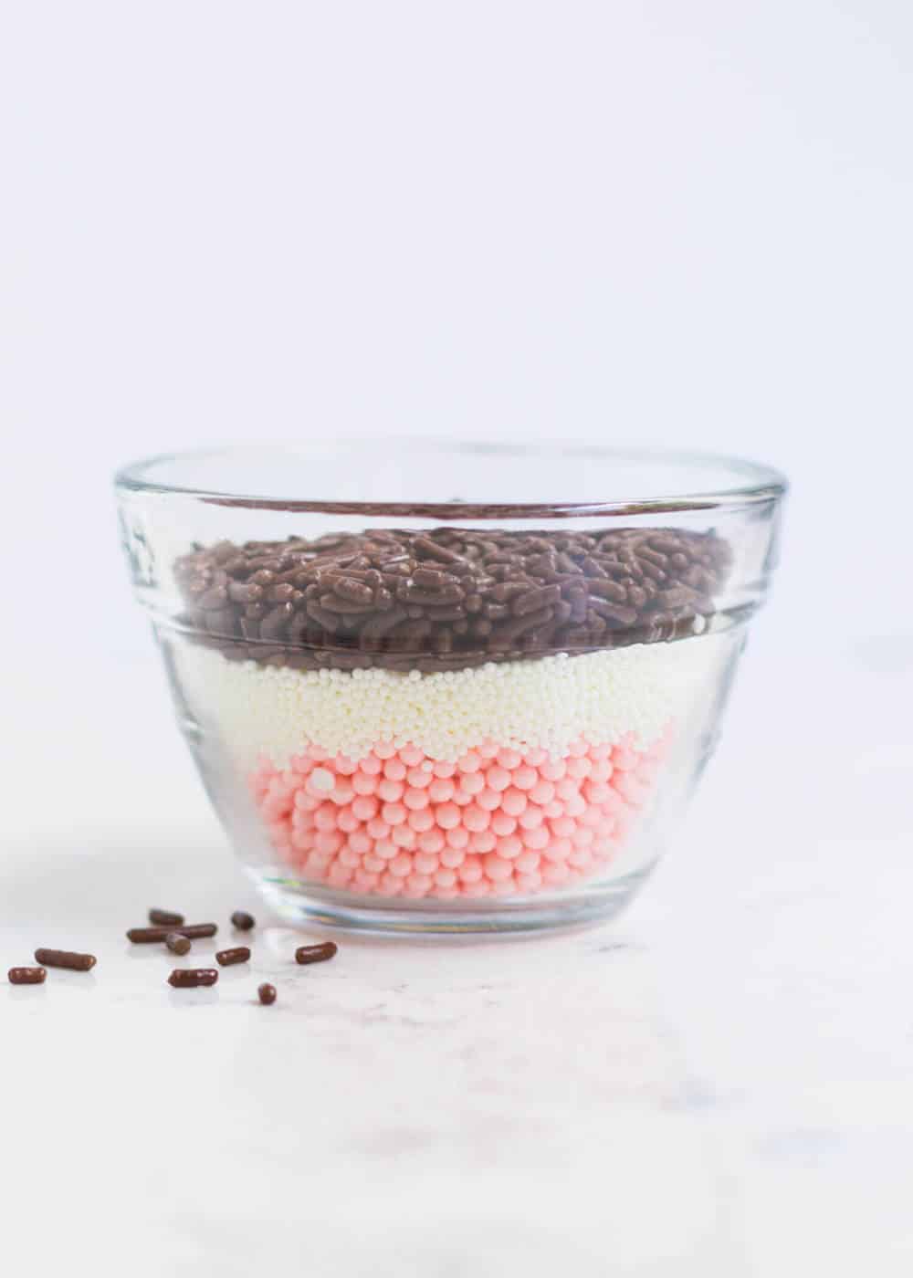 bowl with layers of different types of sprinkles for Neapolitan cake 