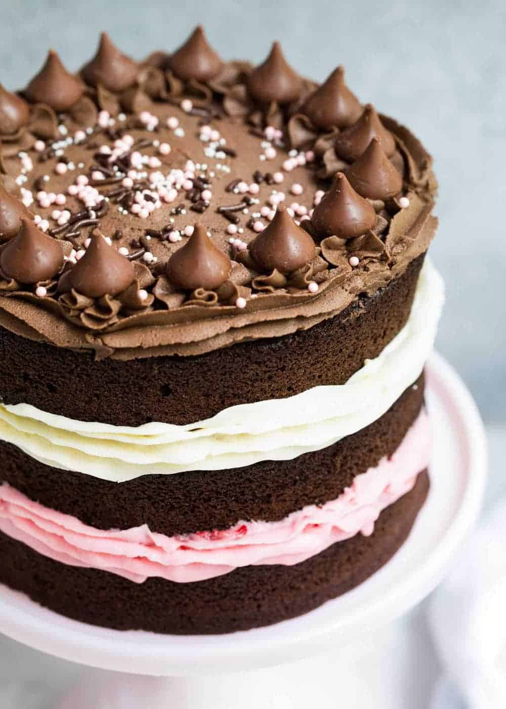 Neapolitan cake on a white cake stand 