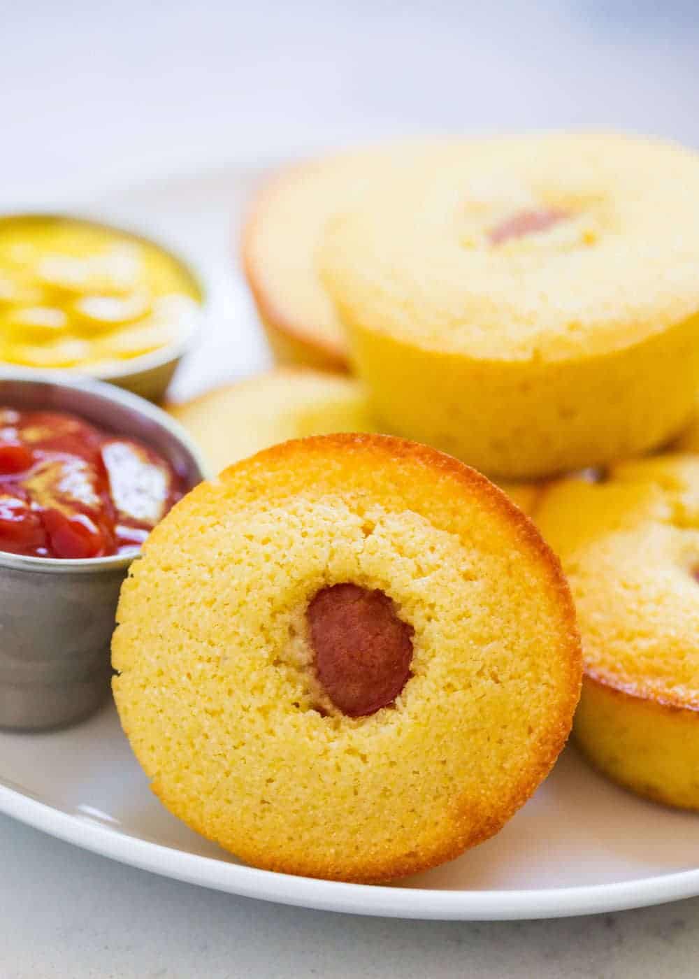 Corn dog muffins on a plate with ketchup and mustard.