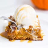 A piece of pumpkin cake on a plate with ice cream on top