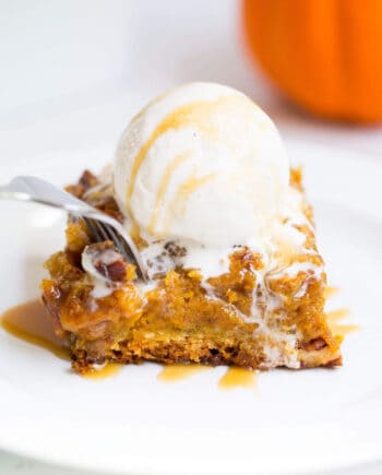 A piece of pumpkin cake on a plate with ice cream on top