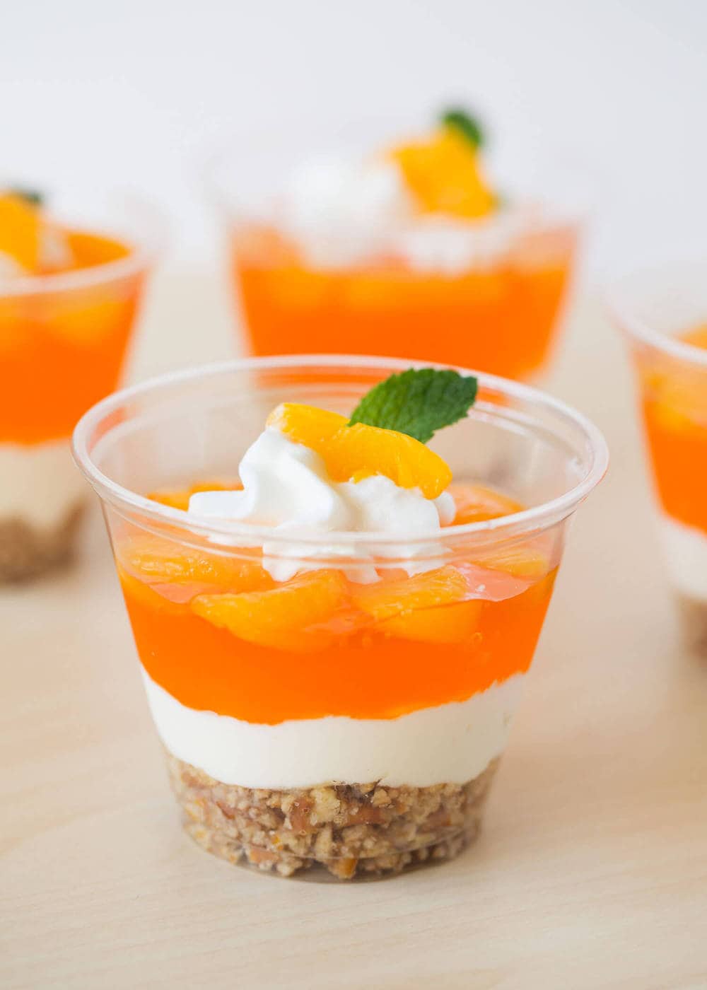 Mandarin orange dessert parfait with whipped cream and a mint leaf on top .