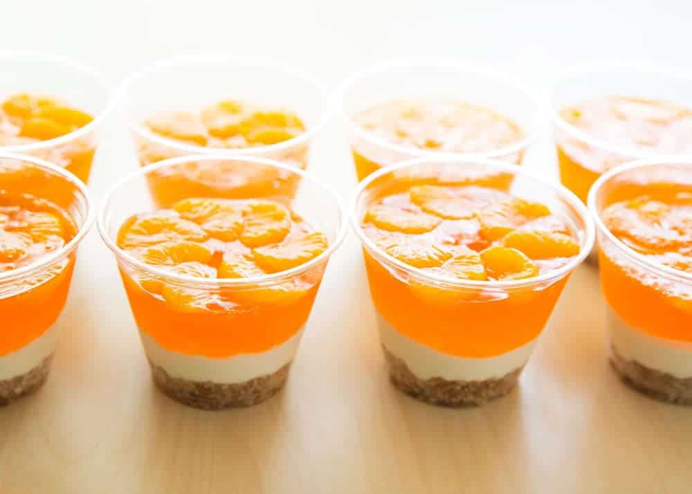 Mandarin orange pretzel salad parfait cups lined up on the counter.