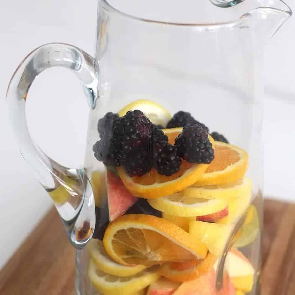 Sliced fruit in a glass pitcher.