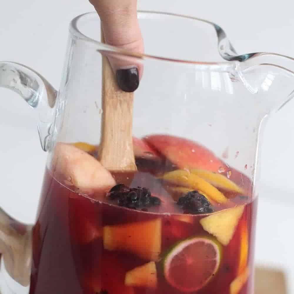 Stirring non-alcoholic sangria with a wooden spoon.