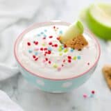 bowl of funfetti dip with an apple slice and graham cracker stick