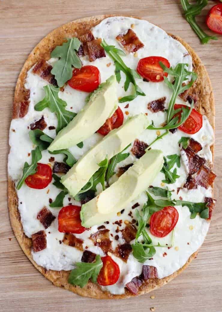 BLT pizza sitting on wood cutting board 