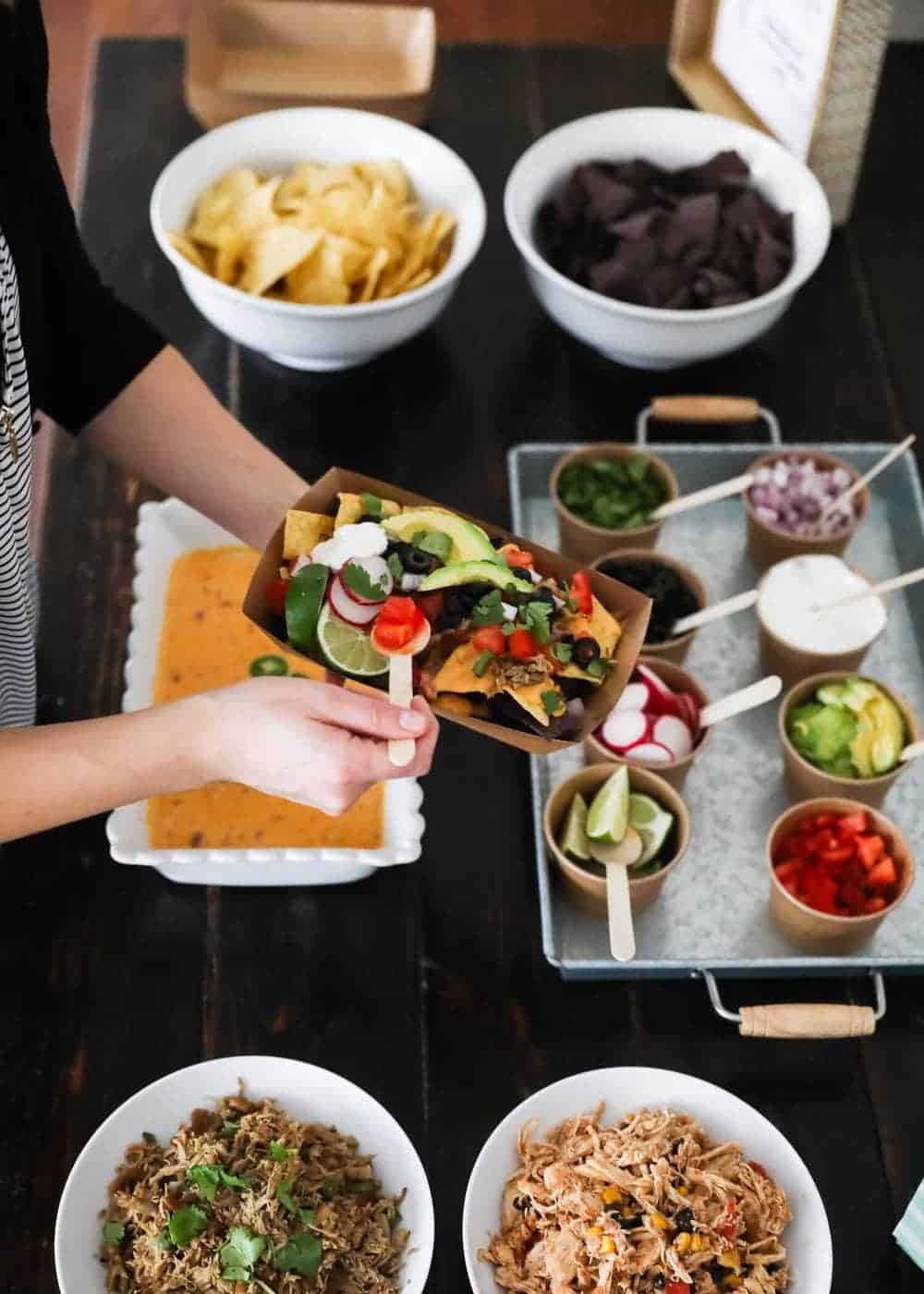 Adding toppings to nachos from a nacho bar.