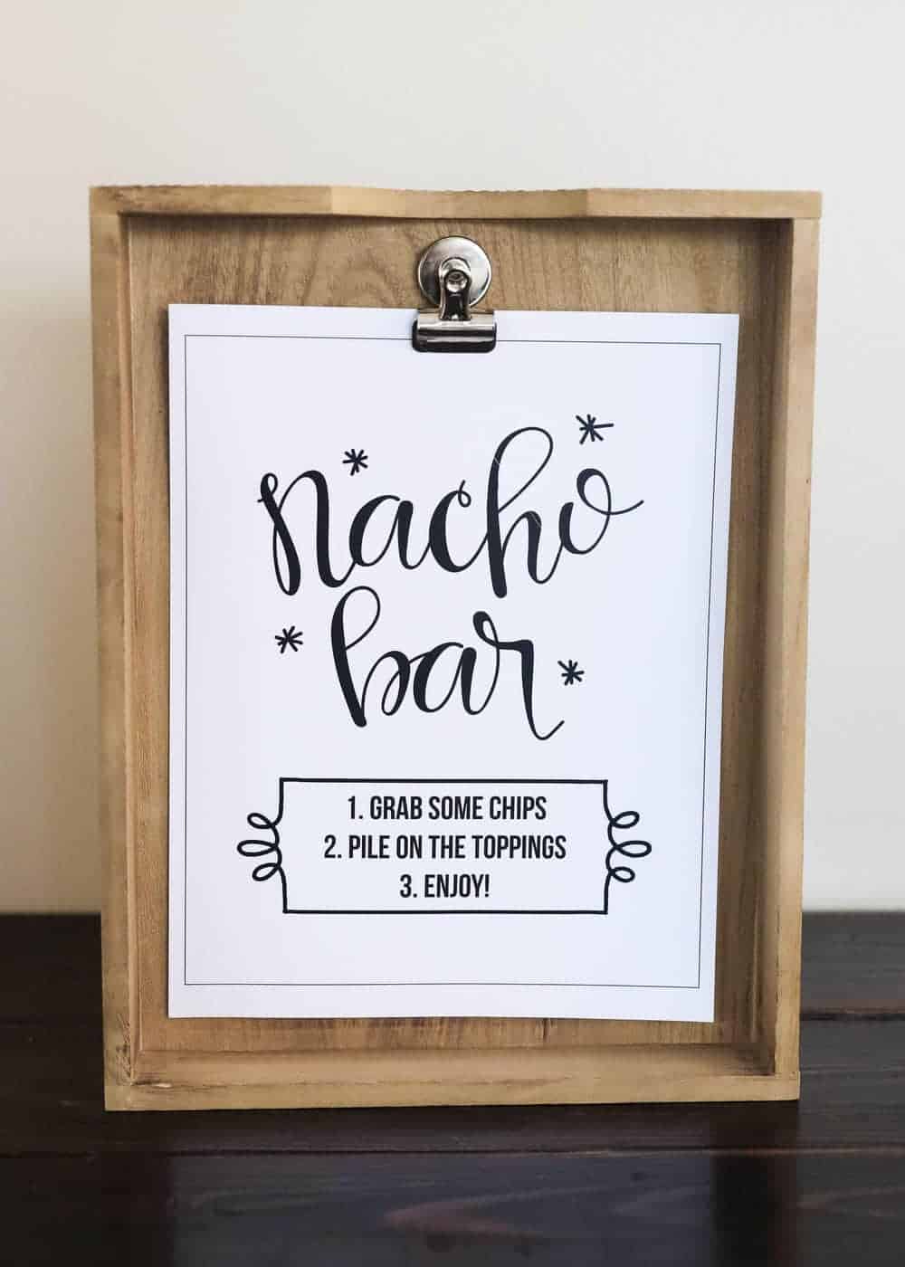 Nacho bar printable sign on a wood clipboard.