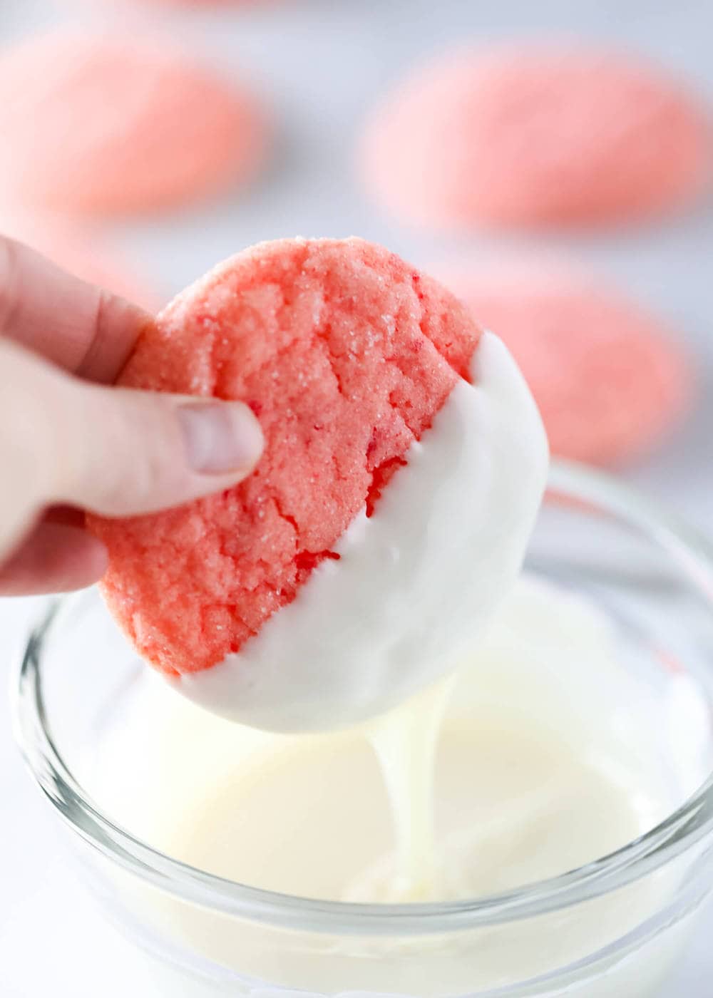 Dipping strawberry cookies in white chocolate.