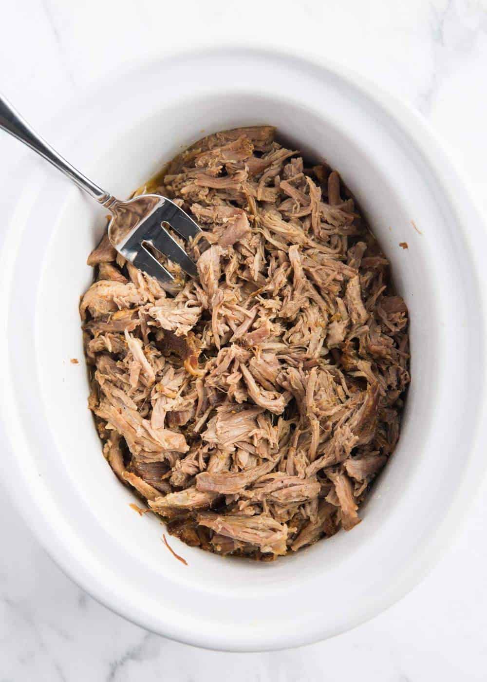 Carnitas in the slow cooker with a fork.
