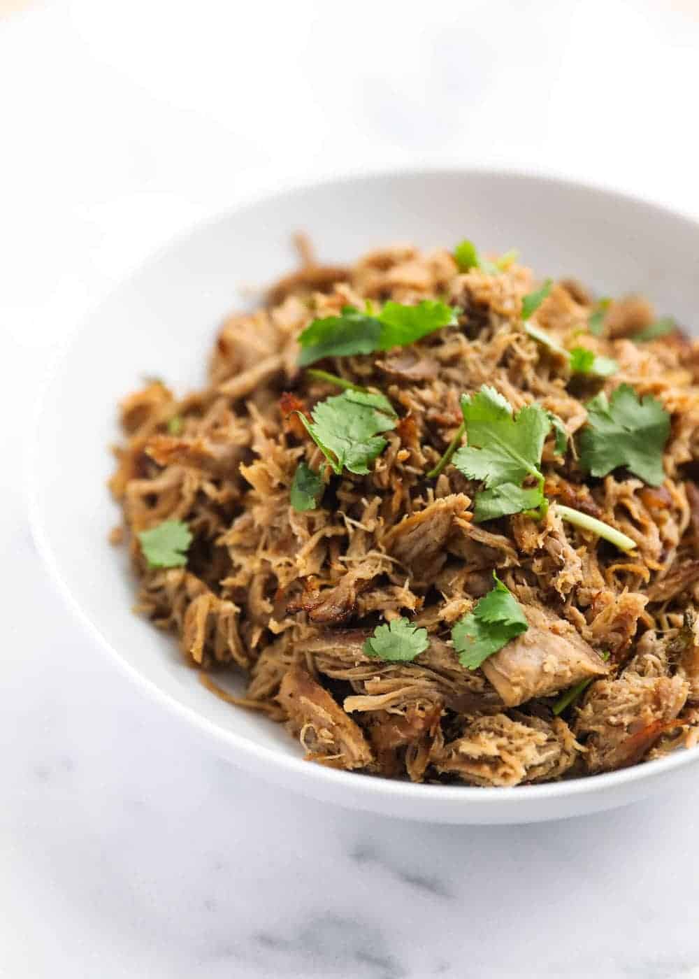 Bowl of crock pot carnitas with cilantro on top.