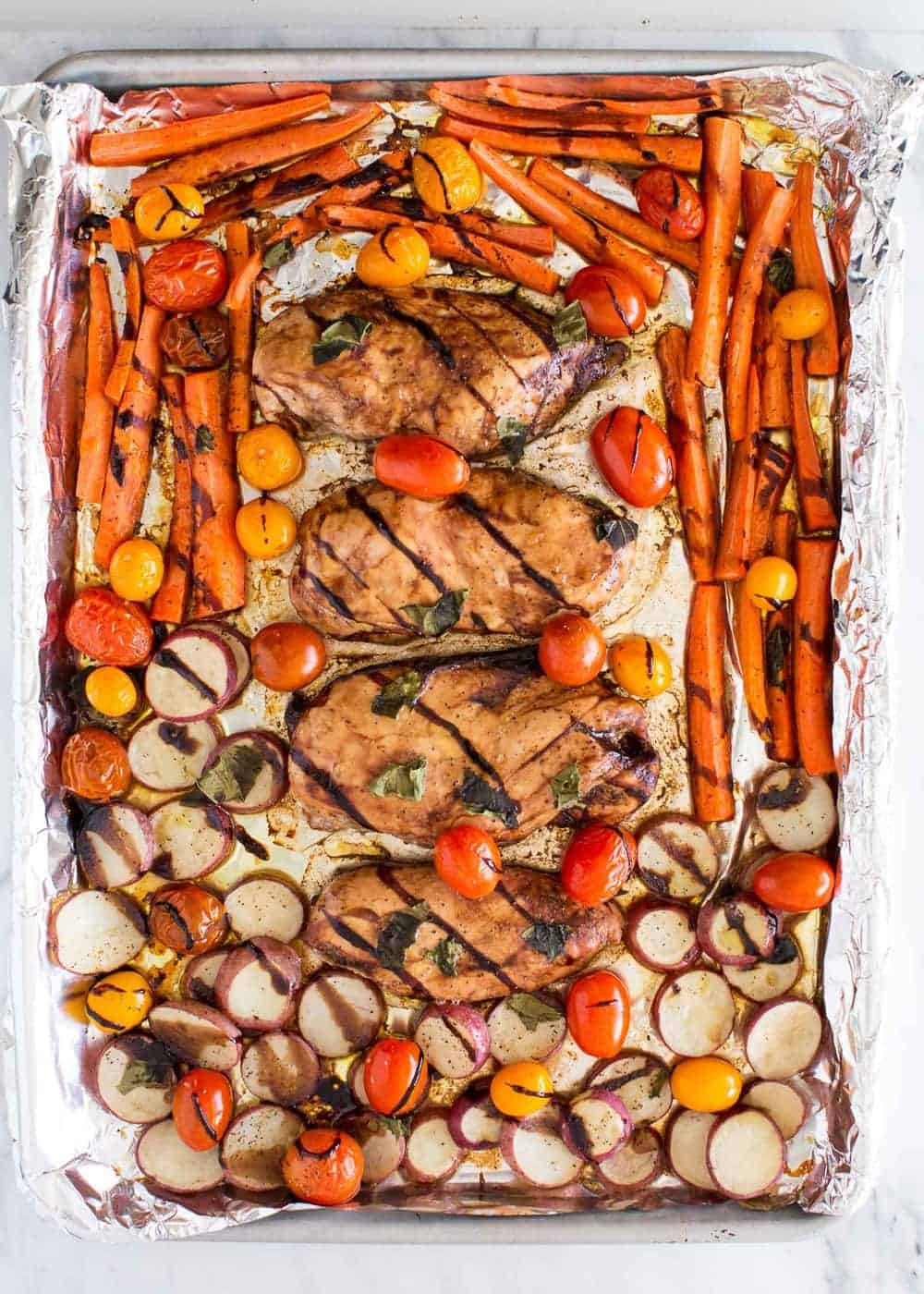 Baked balsamic glazed chicken and vegetables on sheet pan.
