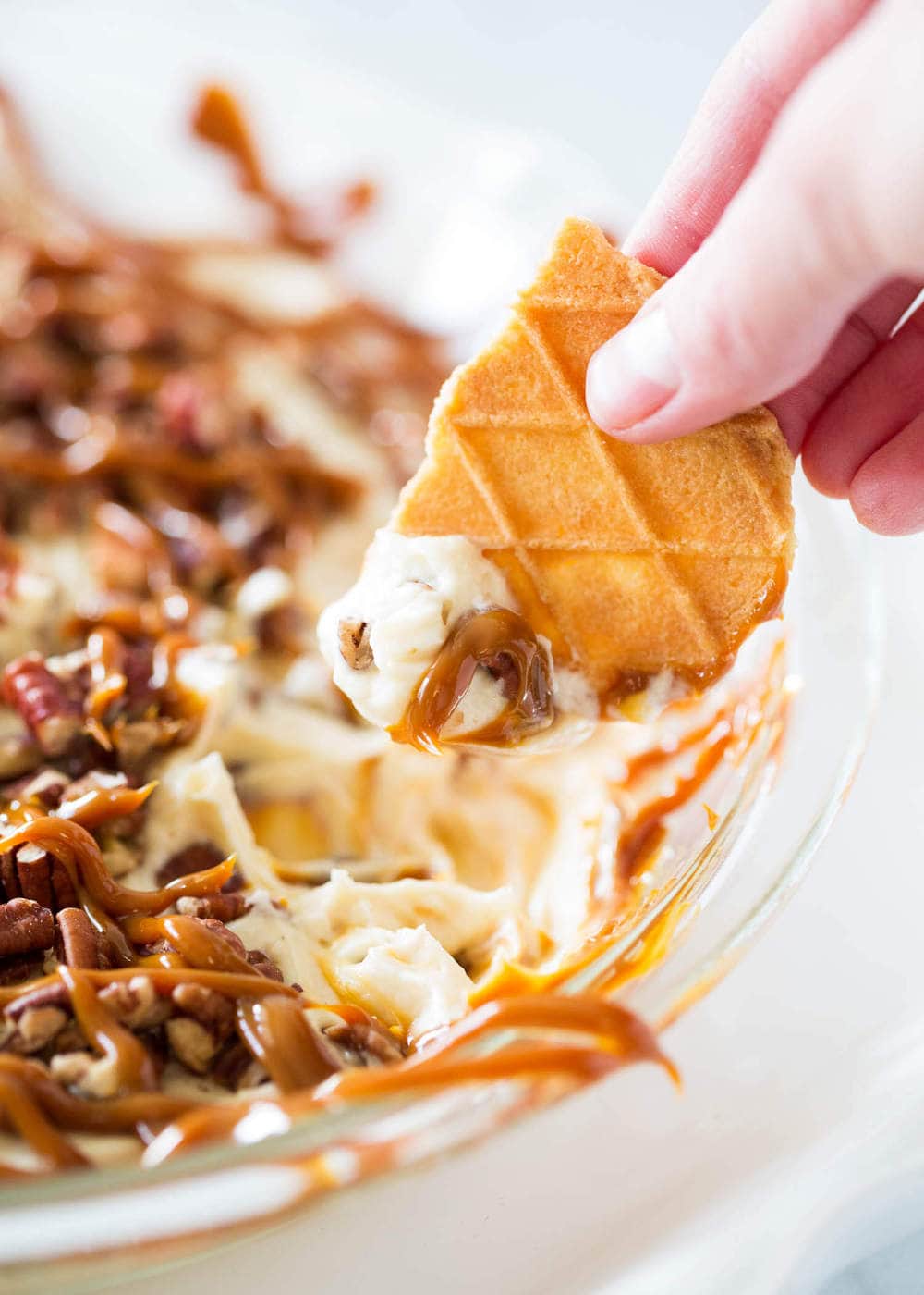 Dipping cookie into caramel pecan cheesecake dip.