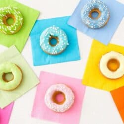 A variety of rainbow donuts on top of colorful napkins