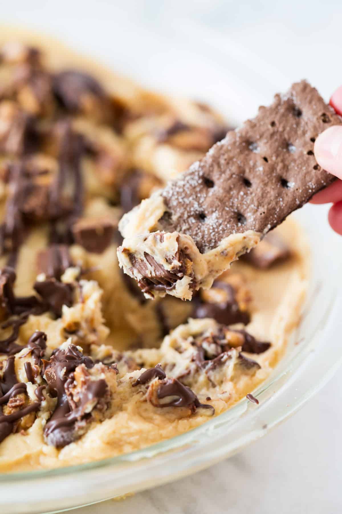 Dipping chocolate graham cracker into peanut butter dip.