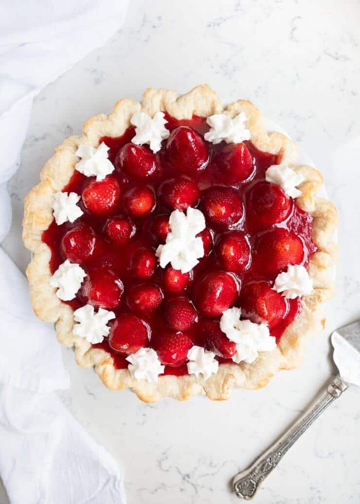 Strawberry cream pie with dollops of whipped cream on top.