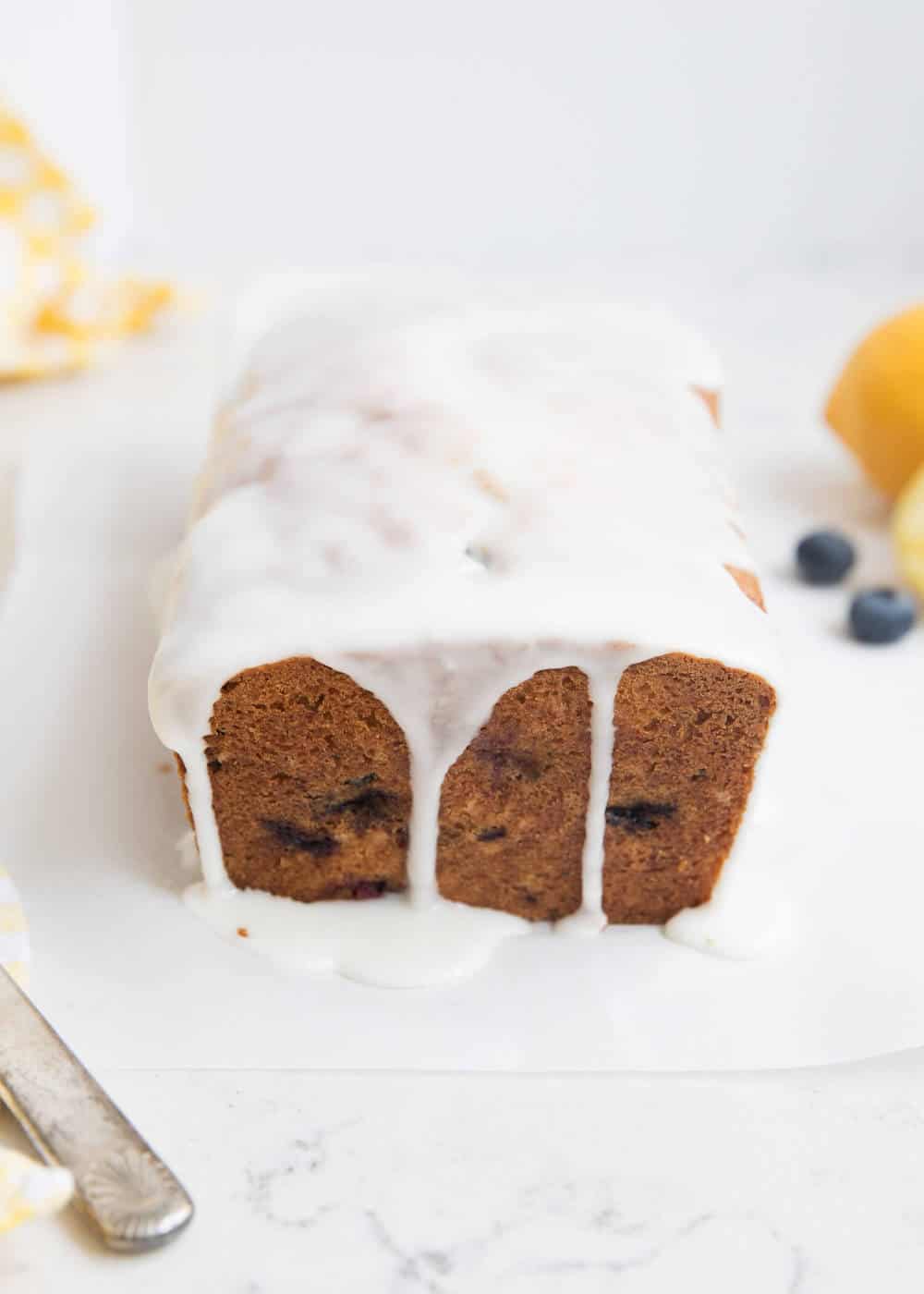 Blueberry zucchini bread with glaze on top and dripping over the sides.