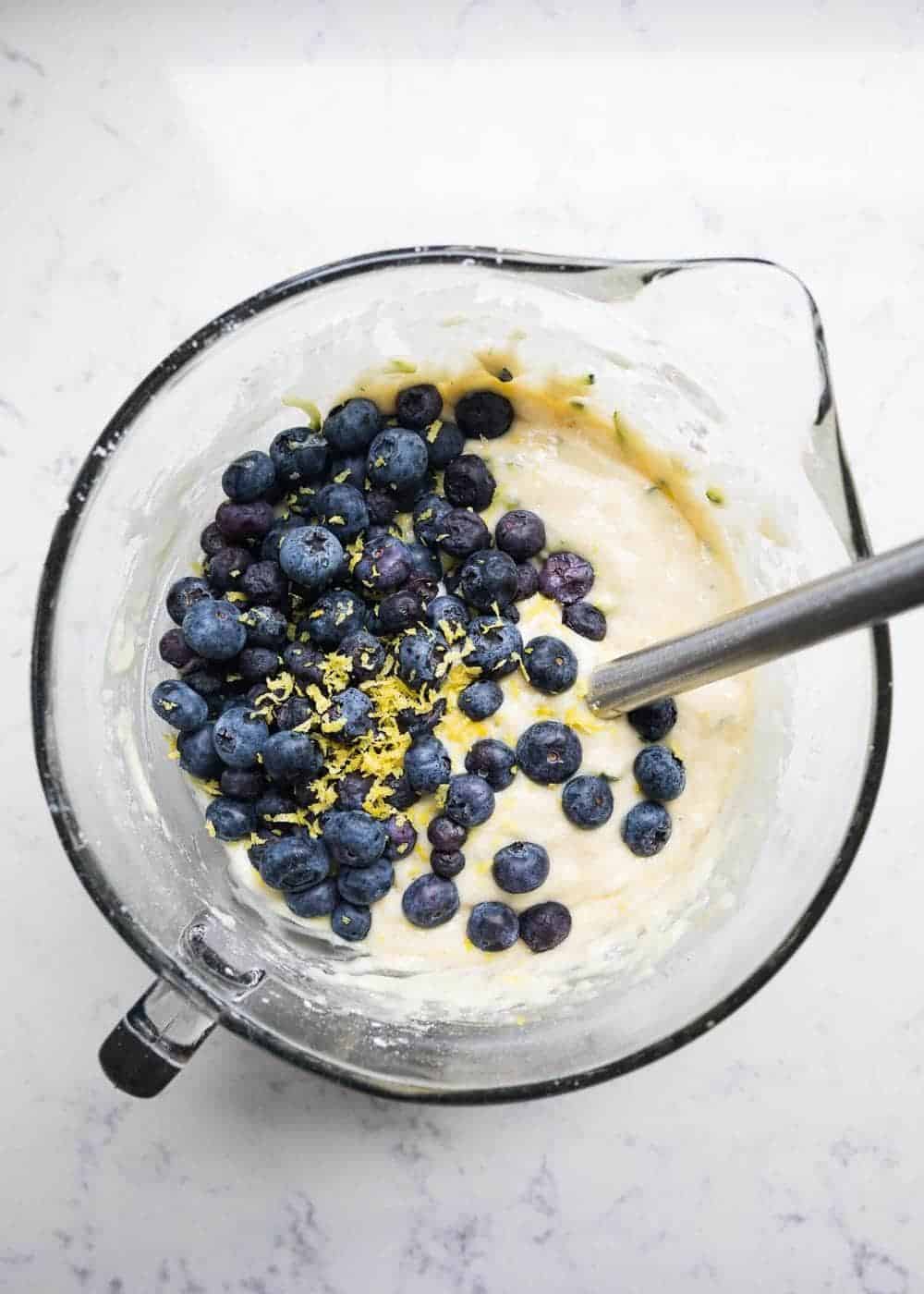 Folding in fresh blueberries and lemon zest to batter.