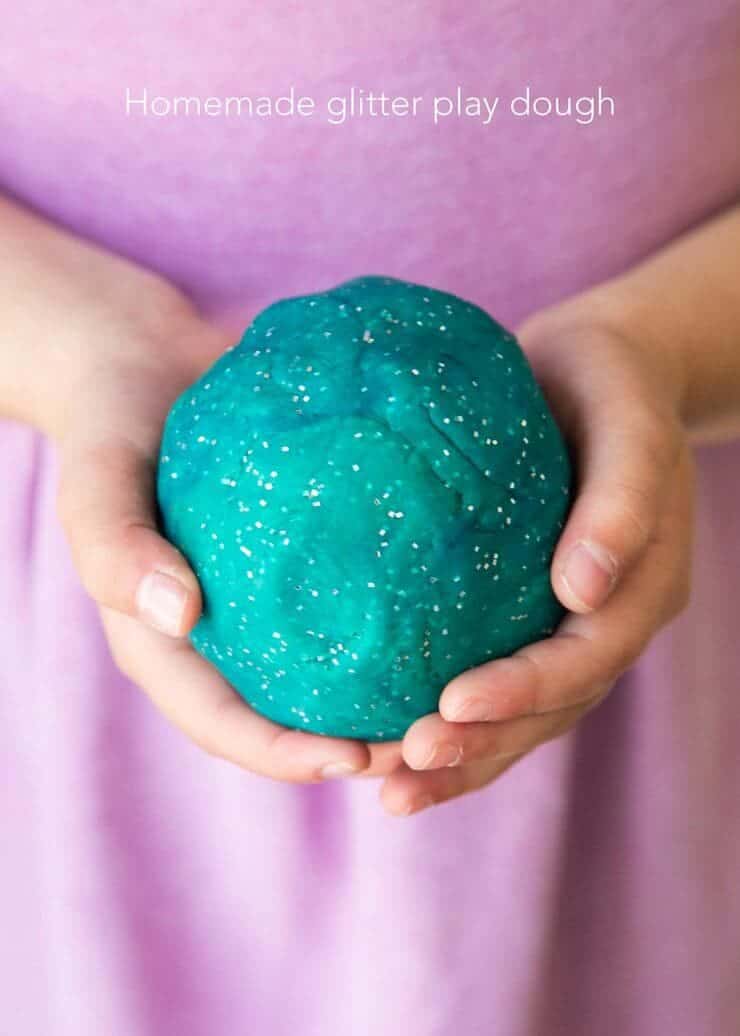 子供の手でティールキラキラプレイ生地ボール's hand