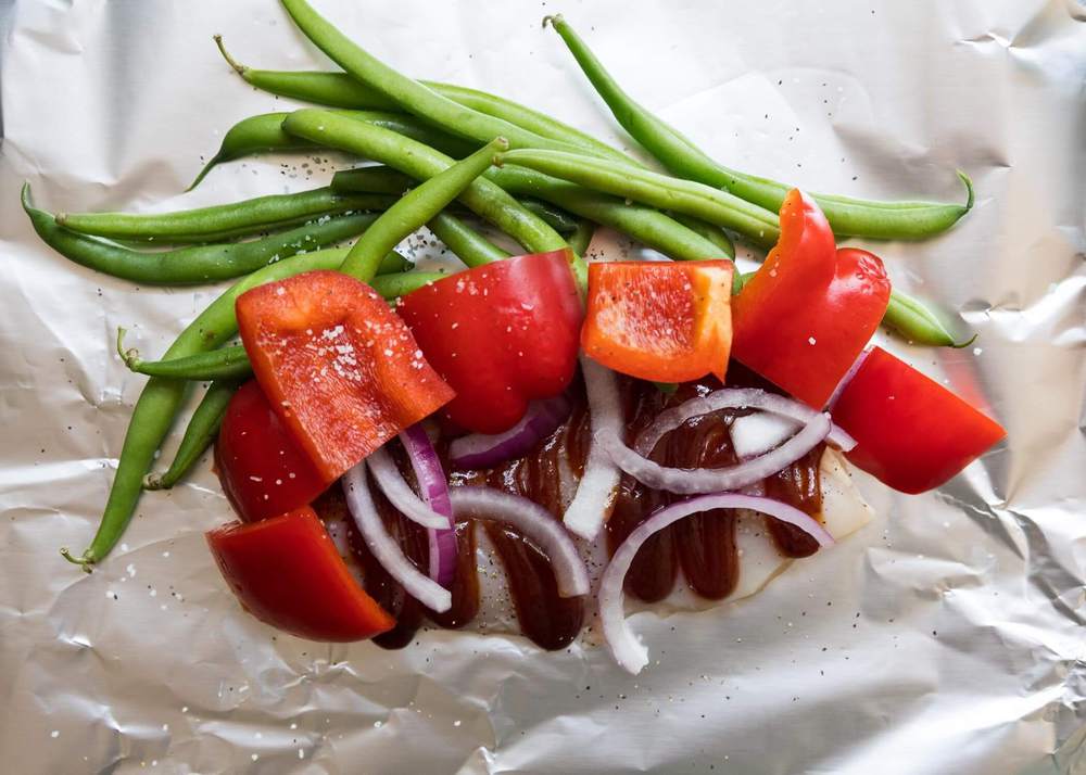 bbq sauce and veggies layered on top of foil 