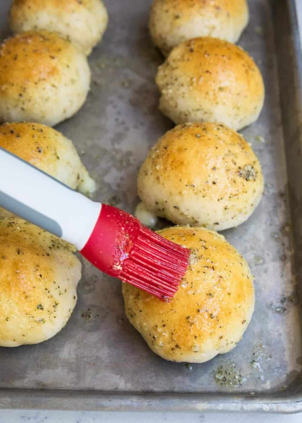 Brushing garlic on top of baked cheese roll.