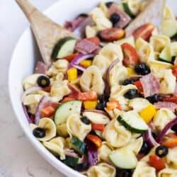 italian tortellini pasta salad in a bowl with a wooden spoon