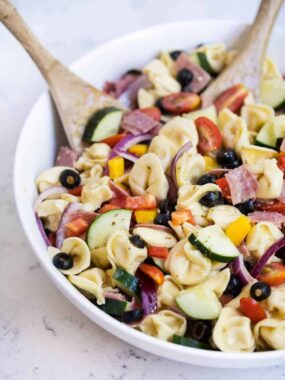 italian tortellini pasta salad in a bowl with a wooden spoon