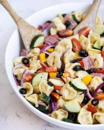 italian tortellini pasta salad in a bowl with a wooden spoon