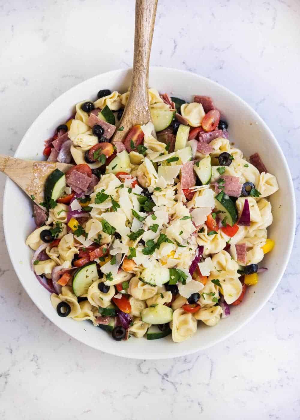 Bowl of tortellini salad with wooden spoon.