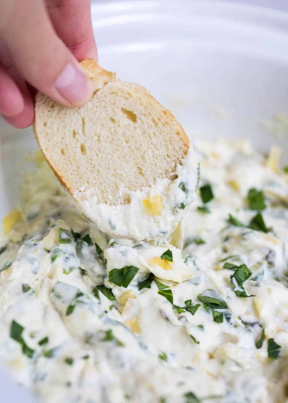 Dipping a french baguette into spinach artichoke dip.