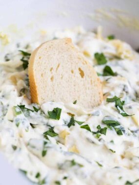 baguette slice dipped in spinach artichoke dip