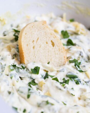 baguette slice dipped in spinach artichoke dip