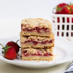 stack of strawberry crumb bars on a white plate