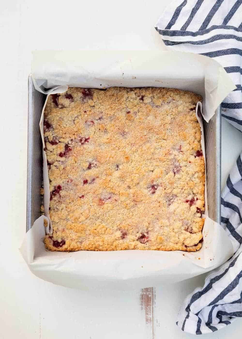 Strawberry crumble bars in a parchment lined pan.