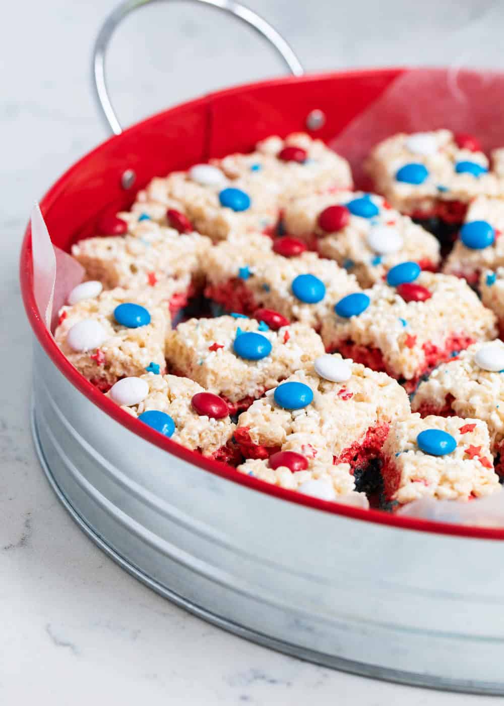 Red white and blue rice krispie treats on a silver and red tray.