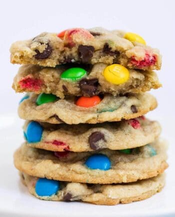 Stack of chewy M&M cookies on a white plate.