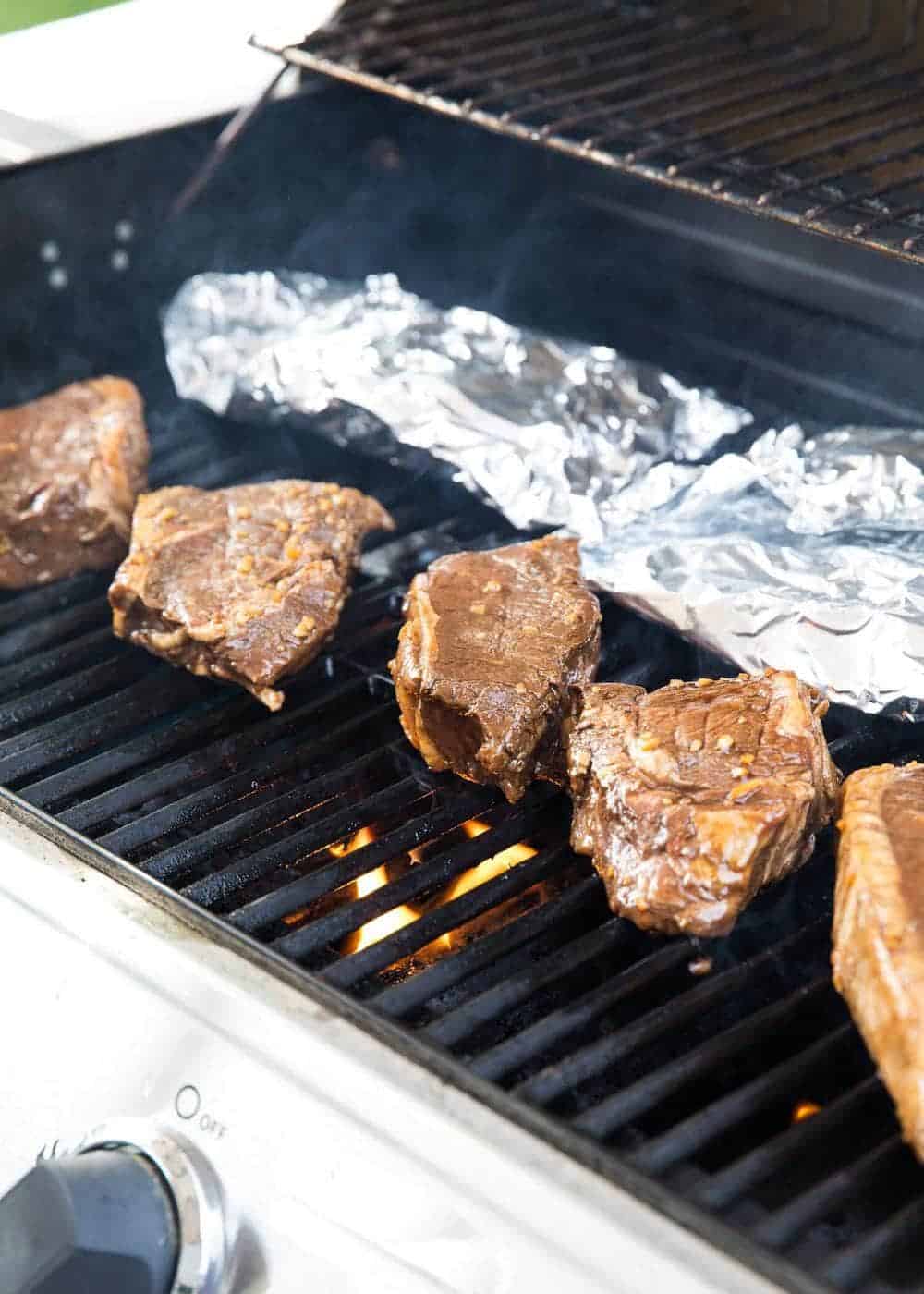 This easy steak marinade takes only 5 ingredients and 5 minutes of prep! The most delicious flavor that creates a tender and juicy steak. steaks cooking on grill