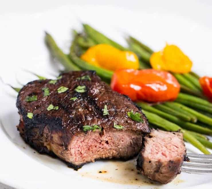 This easy steak marinade takes only 5 ingredients and 5 minutes of prep! The most delicious flavor that creates a tender and juicy steak. grilled steak with grilled green beans and tomatoes on a white plate