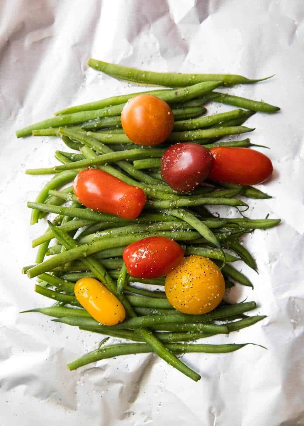 This easy steak marinade takes only 5 ingredients and 5 minutes of prep! The most delicious flavor that creates a tender and juicy steak. seasoned green beans and tomatoes on a piece of foil