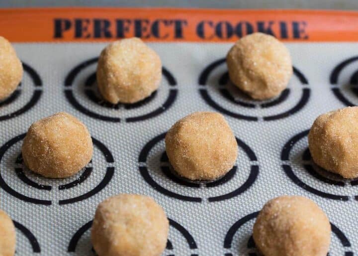 snickerdoodle cookie dough balls on a silicone cookie mat 