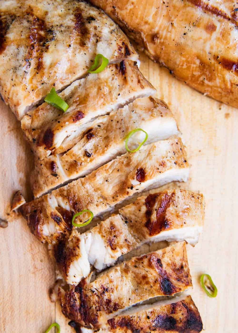 Sliced grilled chicken on cutting board.